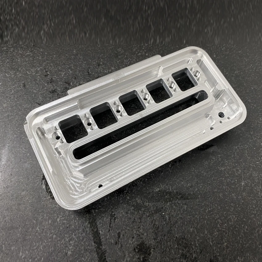 CNC milled aluminium enclosure tray with rectangular pockets, a long slot and tapped holes, machined by GY Machining