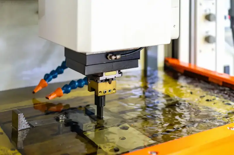 Wire EDM brass wire cutting a steel plate under dielectric fluid at GY Machining