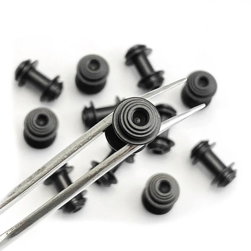 Machined knife pivot barrels and standoffs in black finish, held in tweezers