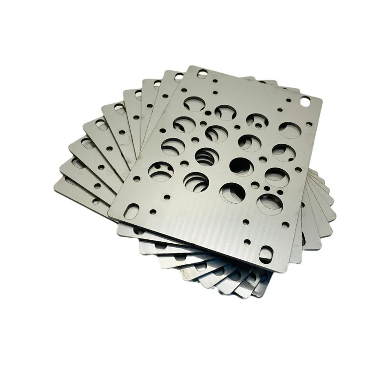 Batch of laser-cut steel mounting plates with holes and slots, stacked after deburring