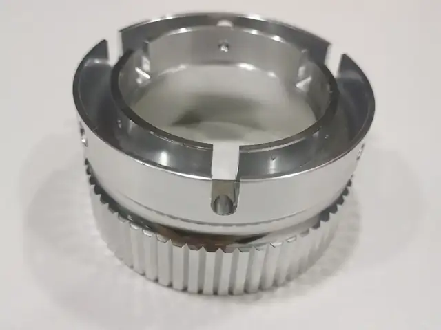 Machined component with milled serrations and precise slots, of the kind used in knife and EDC hardware