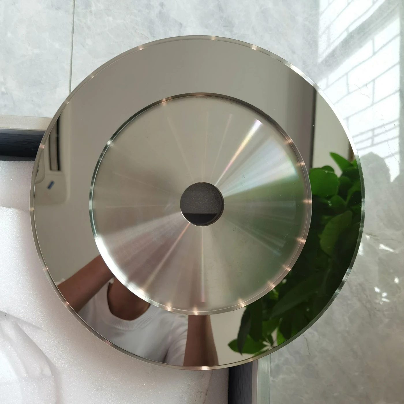 Mirror polished stainless steel disc reflecting the room, with a fine turned centre face