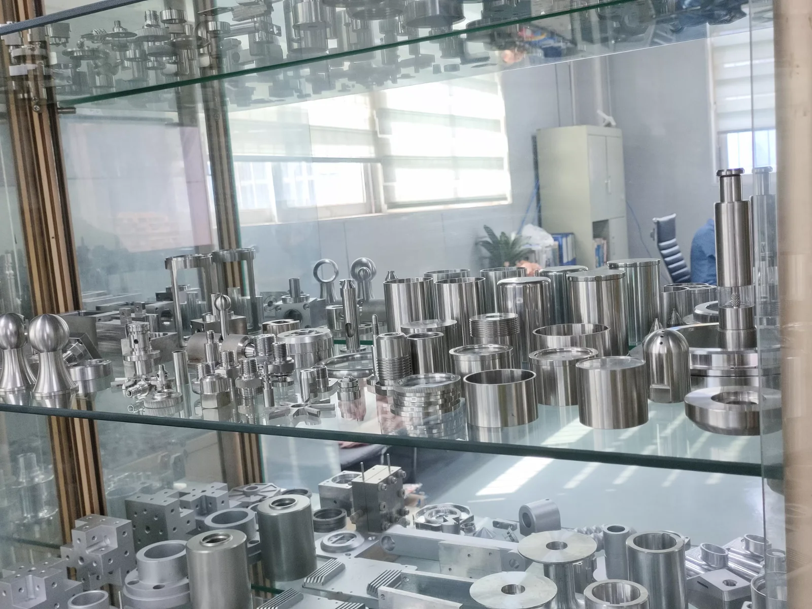 Sample cabinet shelf at GY Machining: stainless steel CNC turned sleeves, caps, fittings, threaded parts and milled aluminium blocks