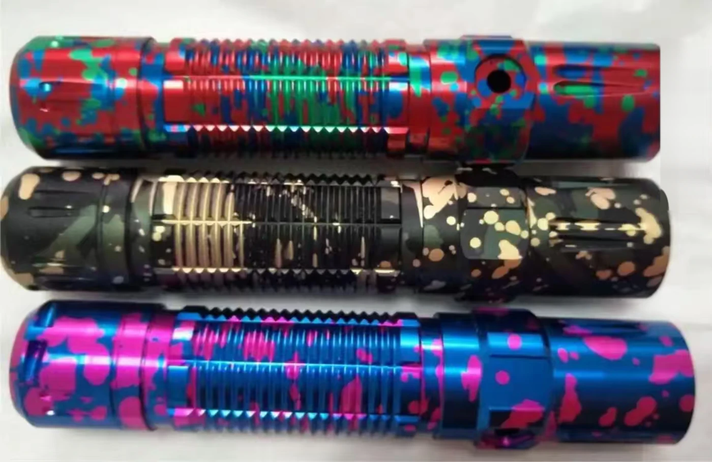 Three CNC machined aluminium flashlight bodies with multi-colour splatter anodised finishes – GY Machining