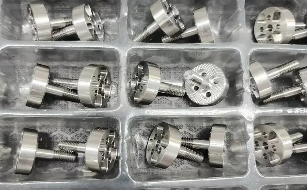 Finished batch of turned and milled stainless steel thumb screws packed in trays at GY Machining