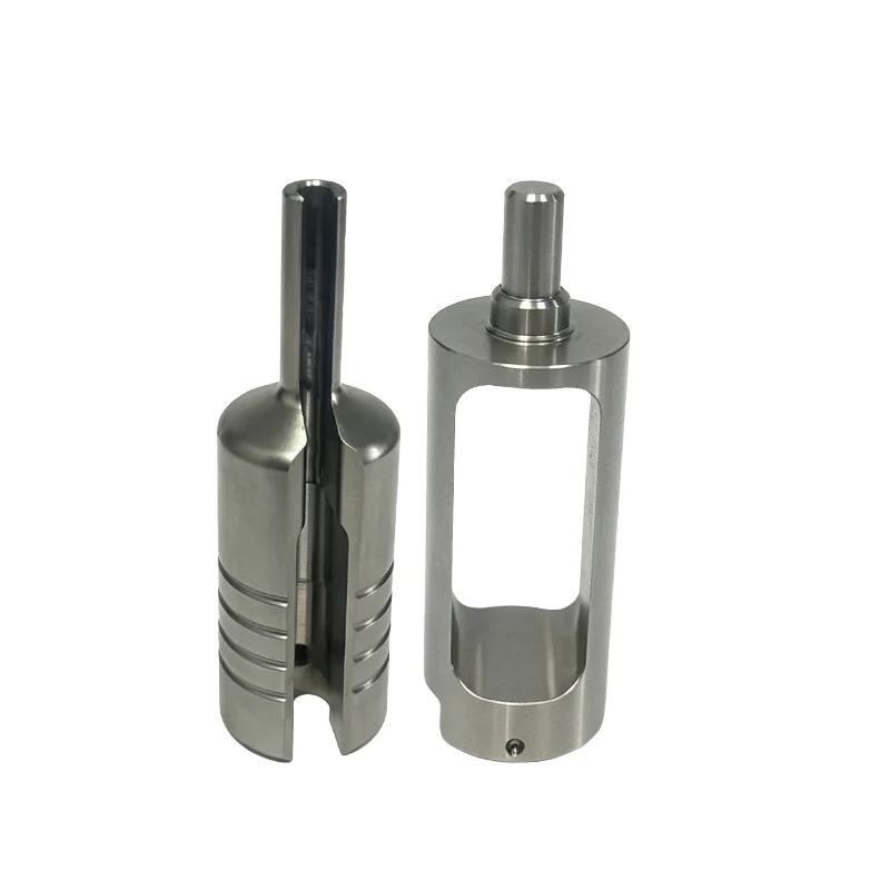 Pair of turned and milled stainless steel cylinders with a through window, slots and a stepped pin