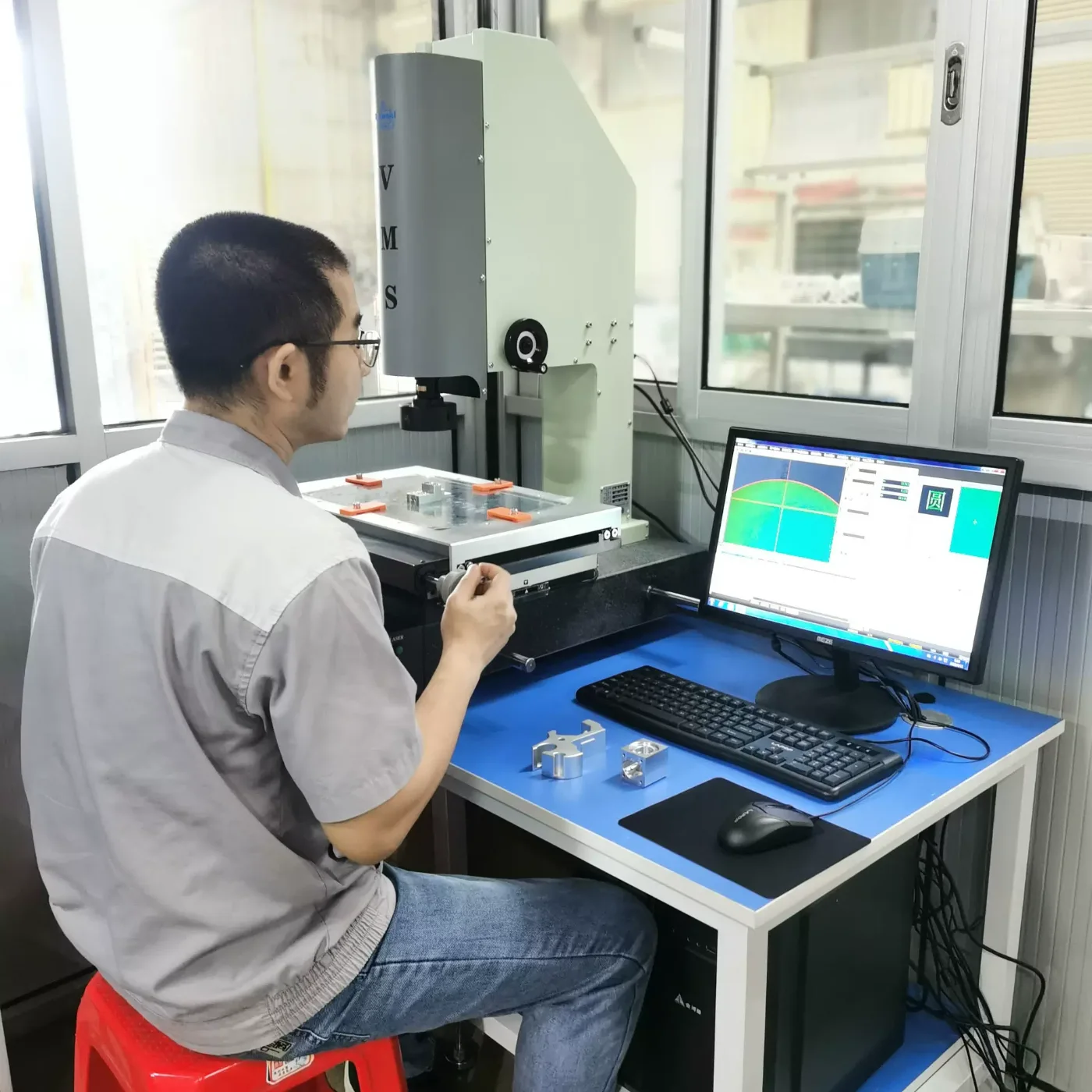 Inspector checking machined aluminium parts on a video measuring system (VMS) in the GY Machining measuring room
